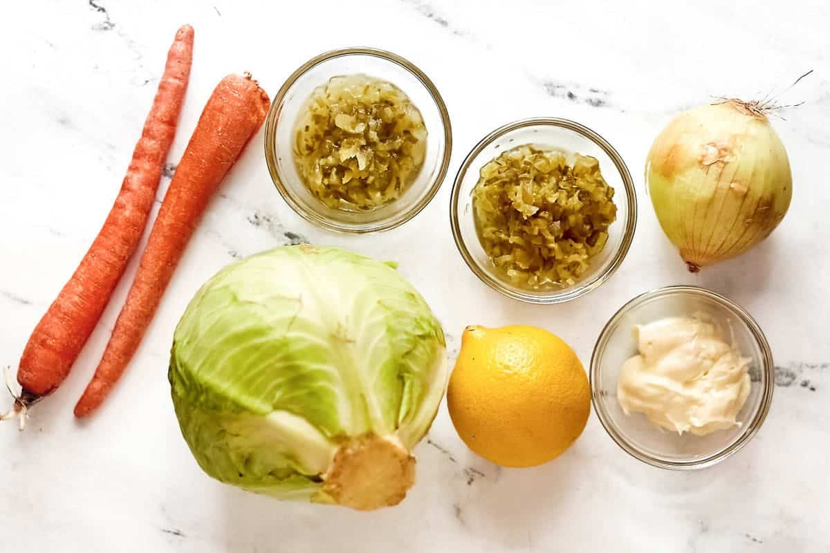 Cabbage, carrots, onion, pickle relish, mayonnaise, vinegar, and lemon.