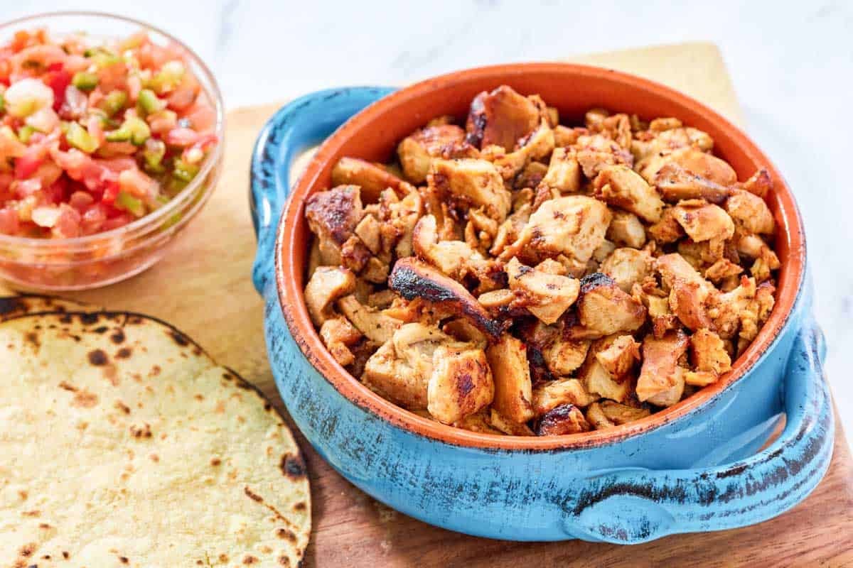 A bowl of mexican sweet, savory, and tangy chicken pieces.