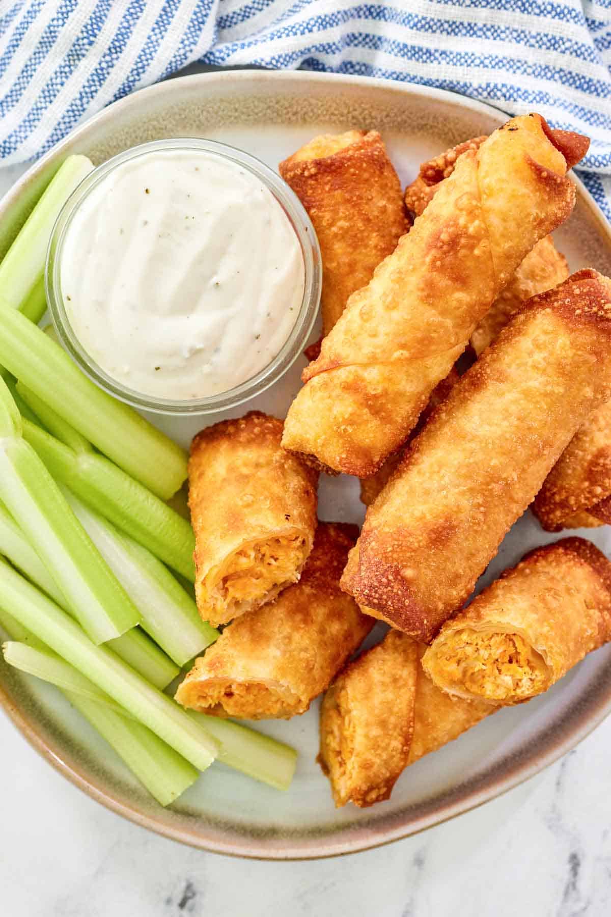 A plate of crispy fried spring rolls filled with Buffalo chicken and cheese.