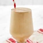 Copycat Arby's jamocha shake with a straw on top of a kitchen towel on a marble surface.
