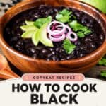 A bowl of cooked black turtle beans topped with avocado slices, onions, and cilantro.
