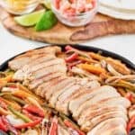 Copycat Chili's chicken fajitas with onions and peppers served with tortillas and toppings.
