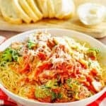 Copycat Olive Garden capellini primavera in a bowl and sliced bread behind it.