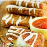 Copycat Olive Garden fried mozzarella sticks and a cup of marinara on a wooden platter.