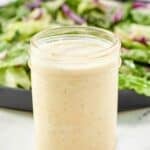 Copycat Olive Garden salad dressing in a mason jar in front of a salad.