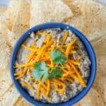 A bowl of restaurant style refried beans surrounded with tortilla chips.