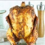 A whole smoked beer can chicken on a marble surface.