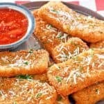 Copycat TGI Friday's crispy fried mozzarella sticks served with marinara sauce.