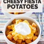 A bowl of spicy Mexican potatoes topped with cheese and sour cream.