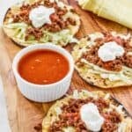 Tostadas and copycat Taco Bell fire sauce on a wood platter.
