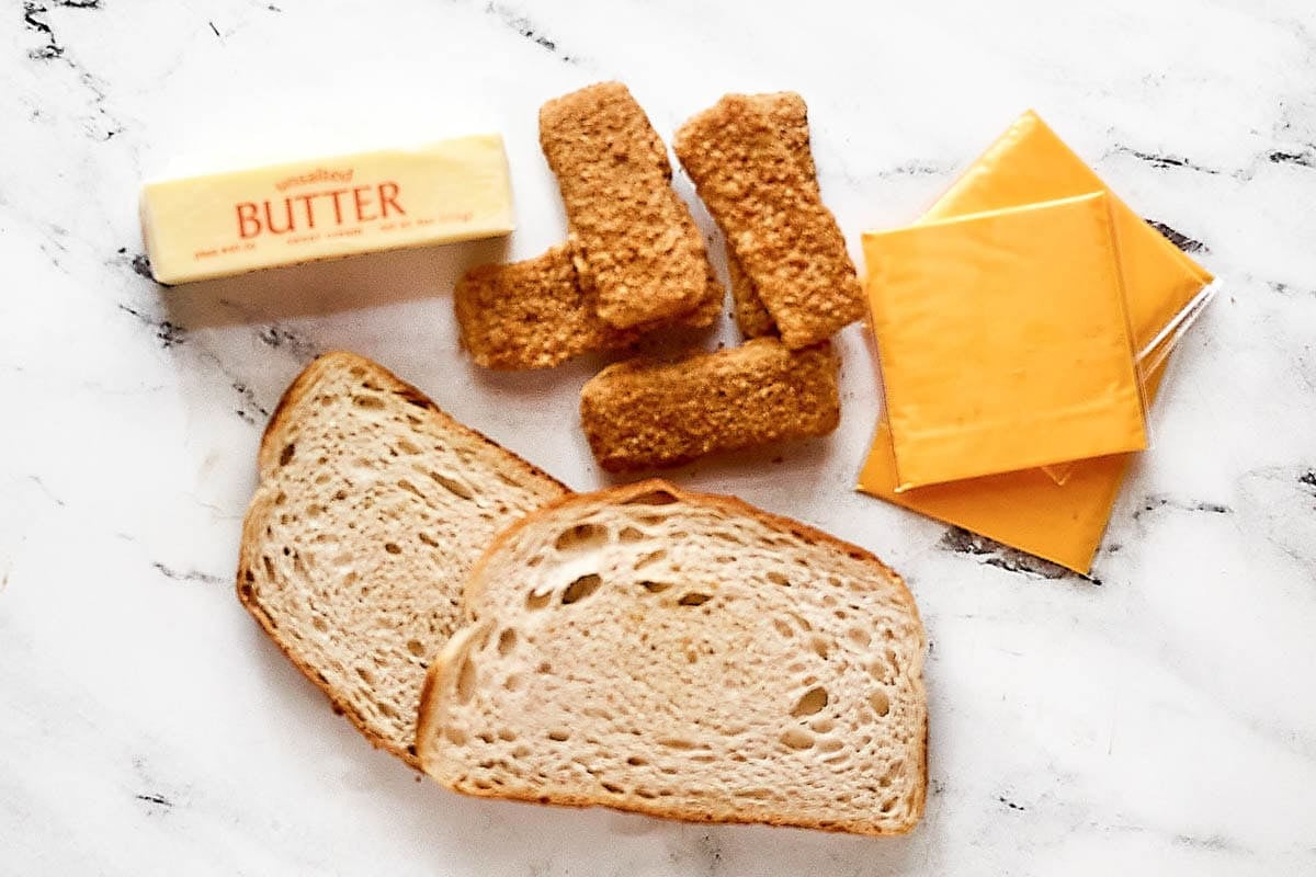 Sourdough bread slices, butter, fried cheese sticks, and American cheese slices.