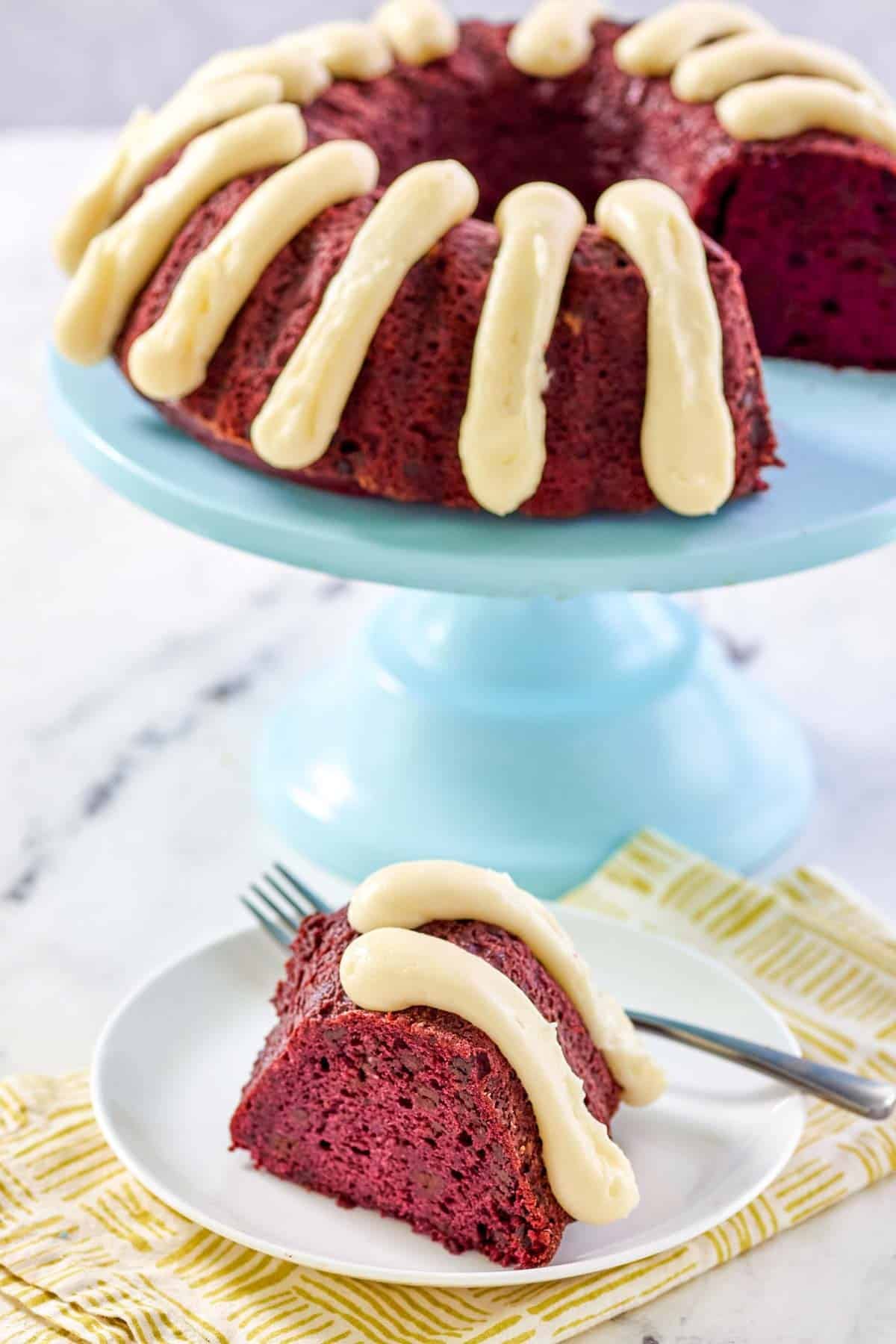 Red velvet chocolate chip bundt cake with cream cheese frosting piped on top.