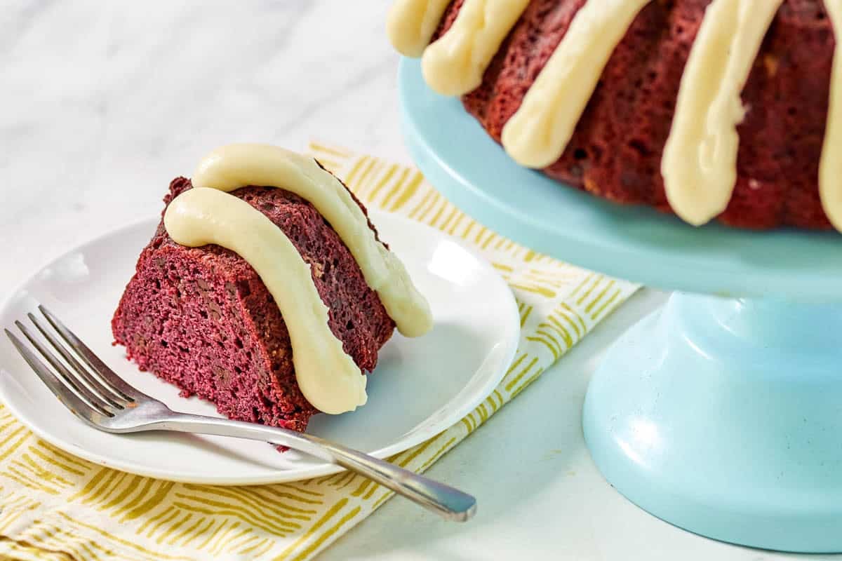 Red velvet chocolate chip bundt cake slice with piped cream cheese frosting.