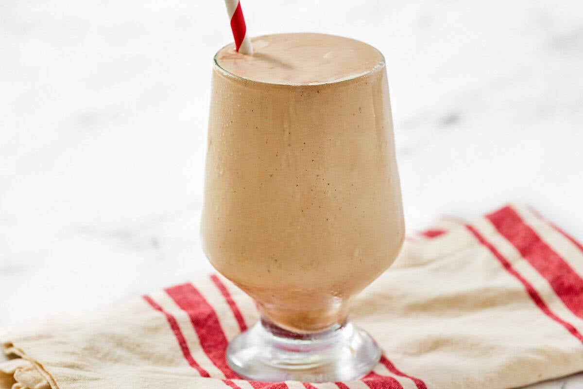 A chocolate coffee milkshake with a straw on a kitchen towel.