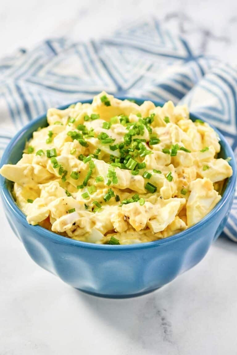 Chunky egg salad in a small bowl and a napkin beside it.