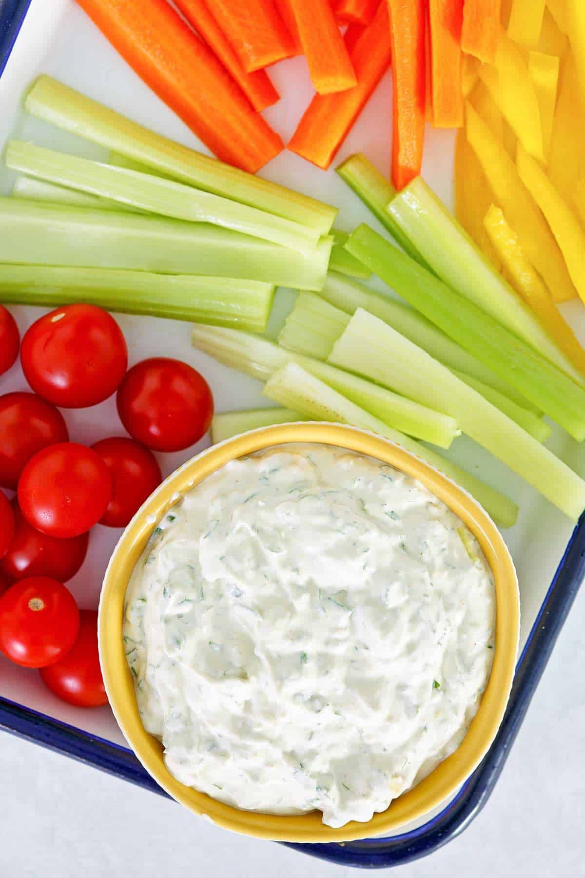 Creamy herb dip with veggies on a platter.