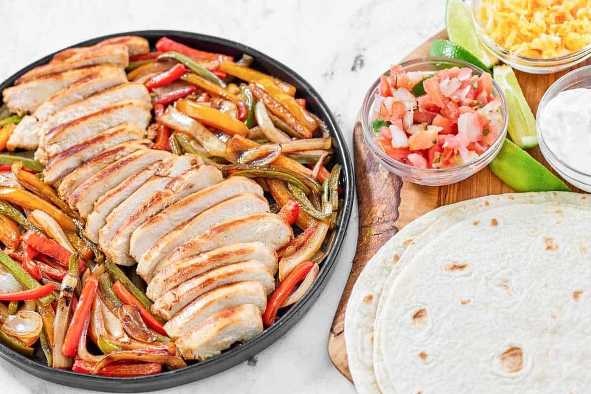 Fajitas with chicken, peppers, and onions served with tortillas, cheese, sour cream, and pico de gallo.