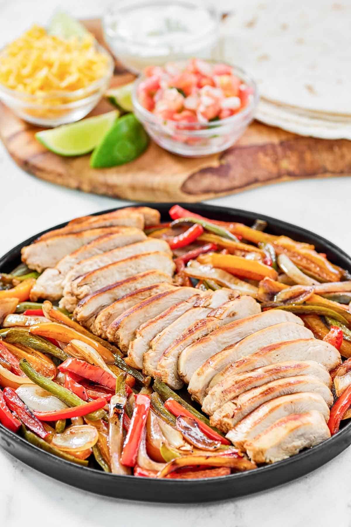 Fajitas with chicken and veggies served with tortillas, cheese, sour cream, and pico de gallo.