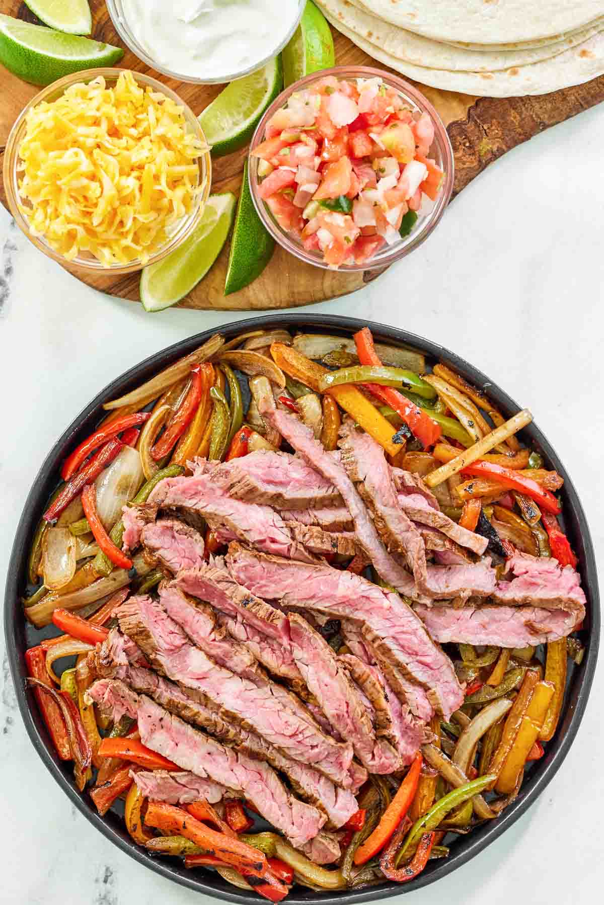 Fajitas with steak and veggies served with tortillas, cheese, pico de gallo, and sour cream.