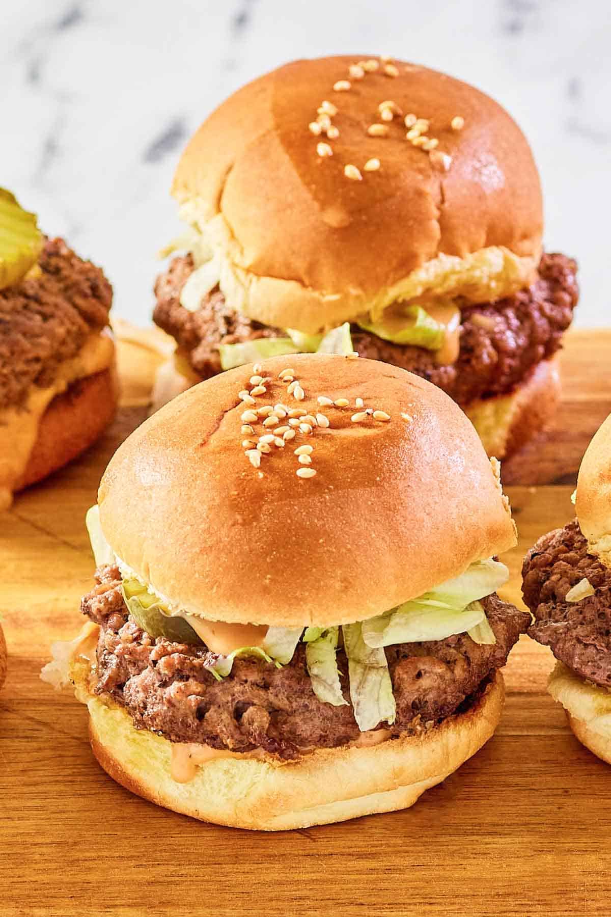 Ground beef and cheese sliders with sauce and toppings.