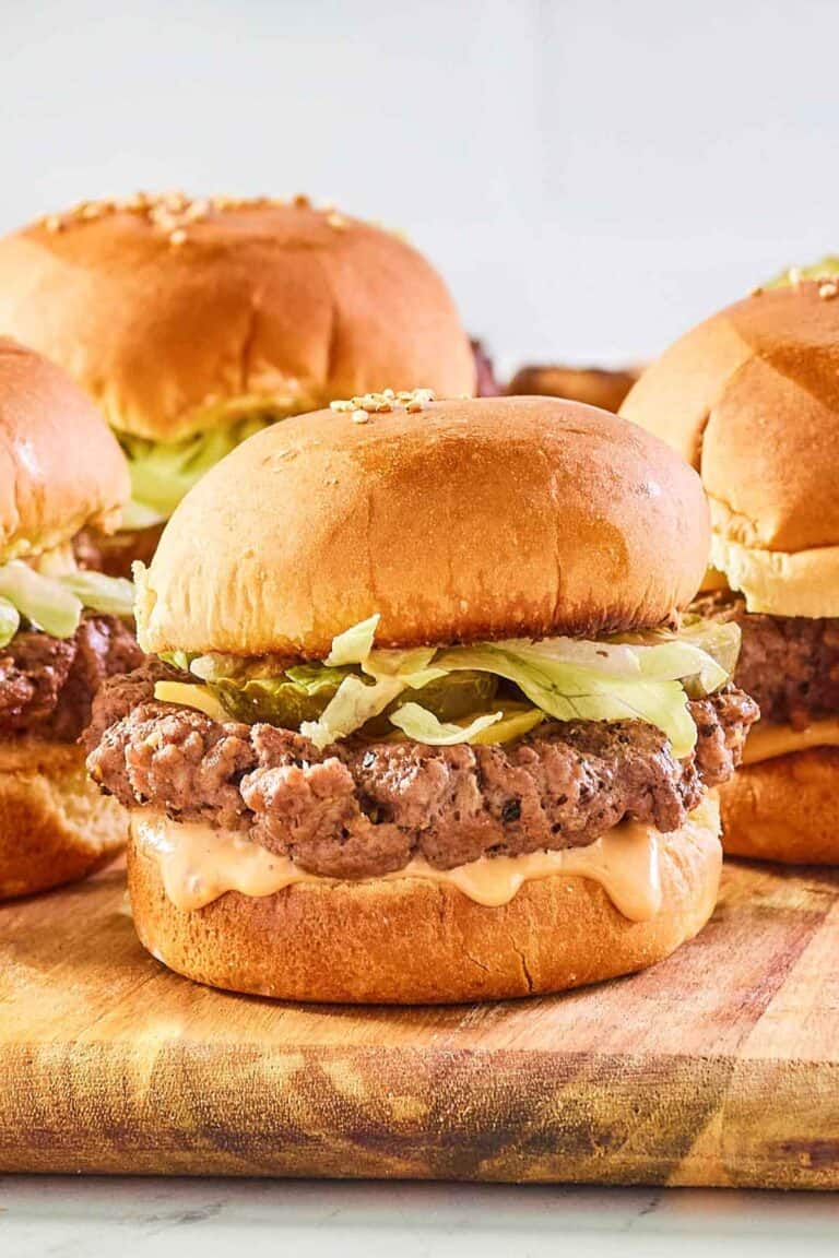 Ground beef sliders with cheese, sauce, and toppings.