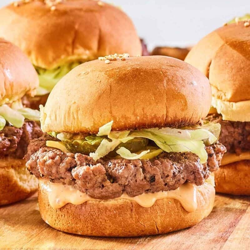 Ground beef sliders with cheese, sauce, and toppings.