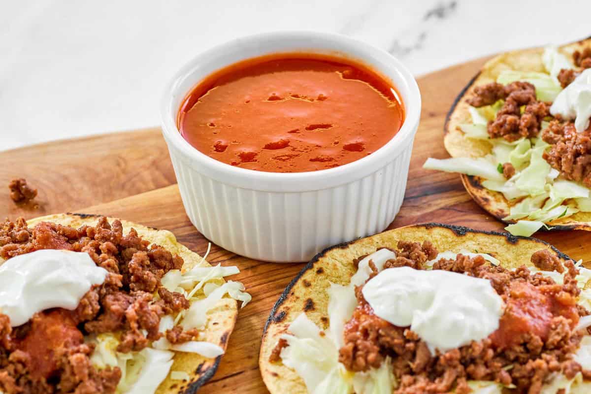 Spicy tomato jalapeno hot sauce in a condiment cup next to tostadas.
