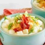 A bowl of copycat Houlihan's baked potato soup topped with bacon, cheese, and green onions.