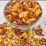 Homemade sweet and salty Chex mix in a serving bowl and scattered in front of it.