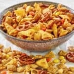 Homemade sweet and salty Chex mix in a bowl and scattered in front of it.