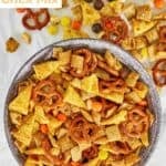 Homemade sweet and salty Chex mix in a bowl and scattered on parchment paper.