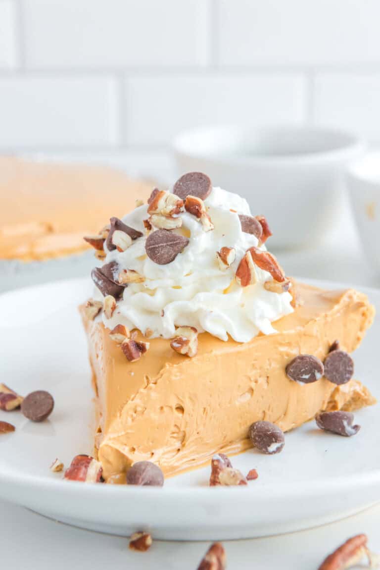 A caramel flavored pie served topped with whipped cream, chopped pecans, and chocolate chips.