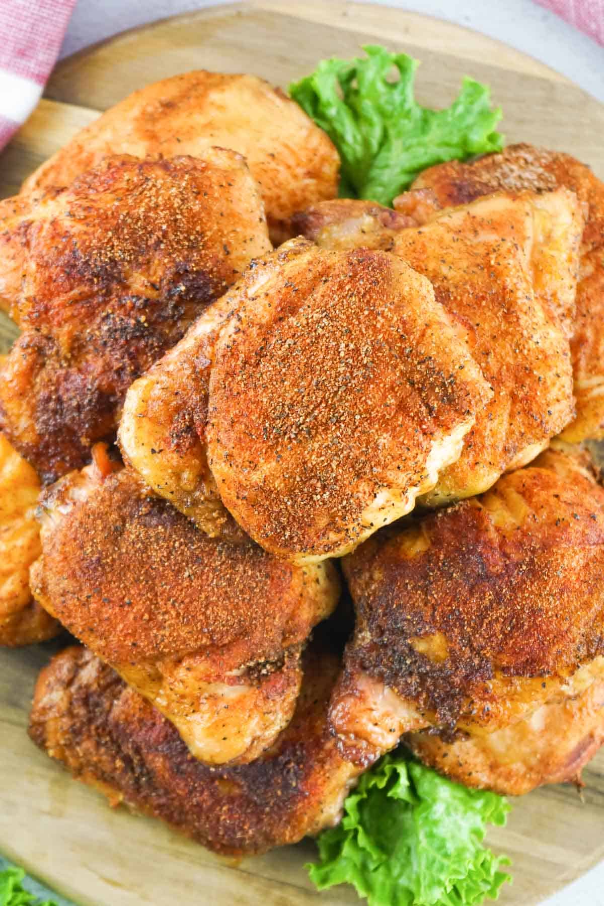 Chicken thighs seasoned and smoked piled on a platter.