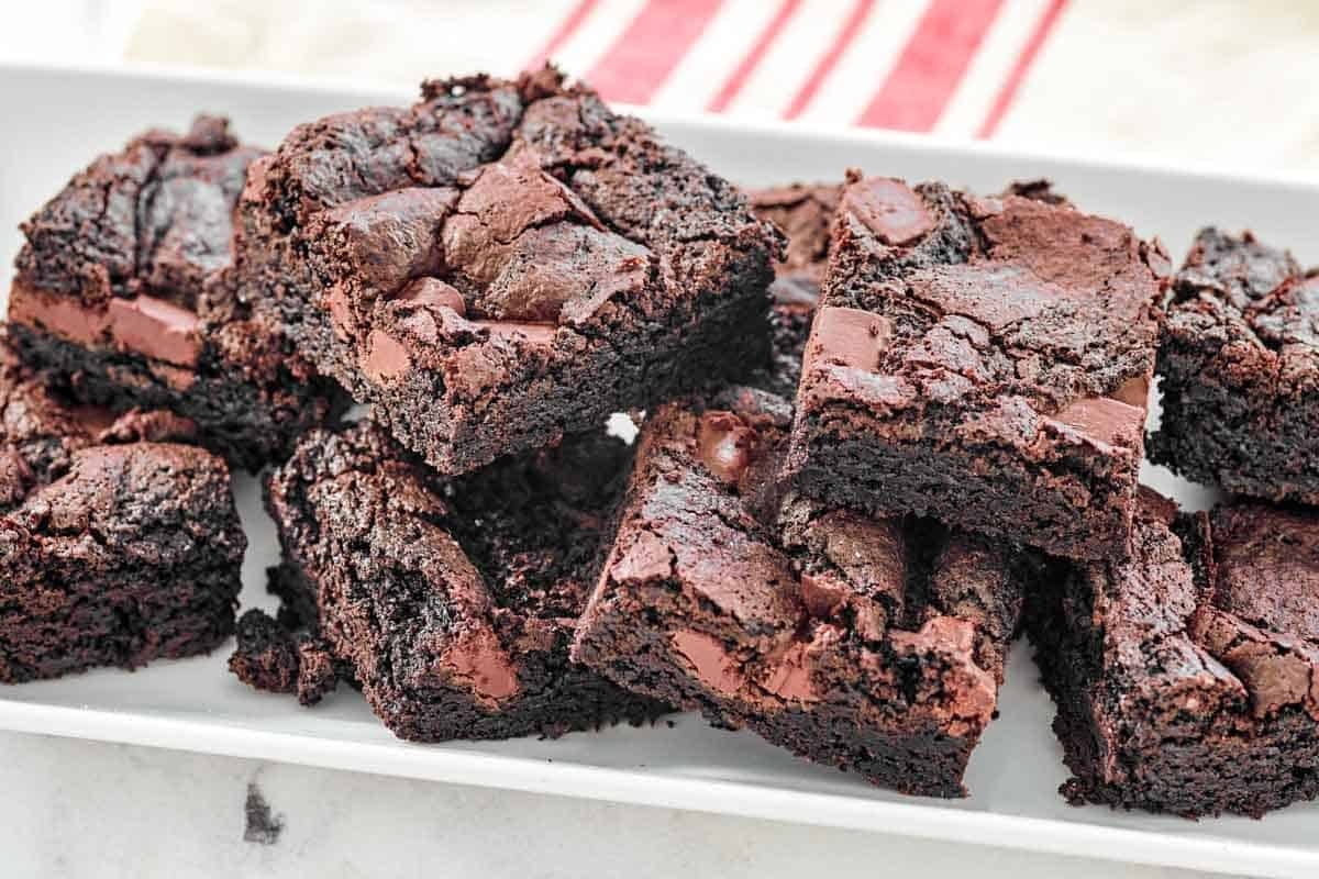 Chocolate chunk fudge brownies piled on a platter.