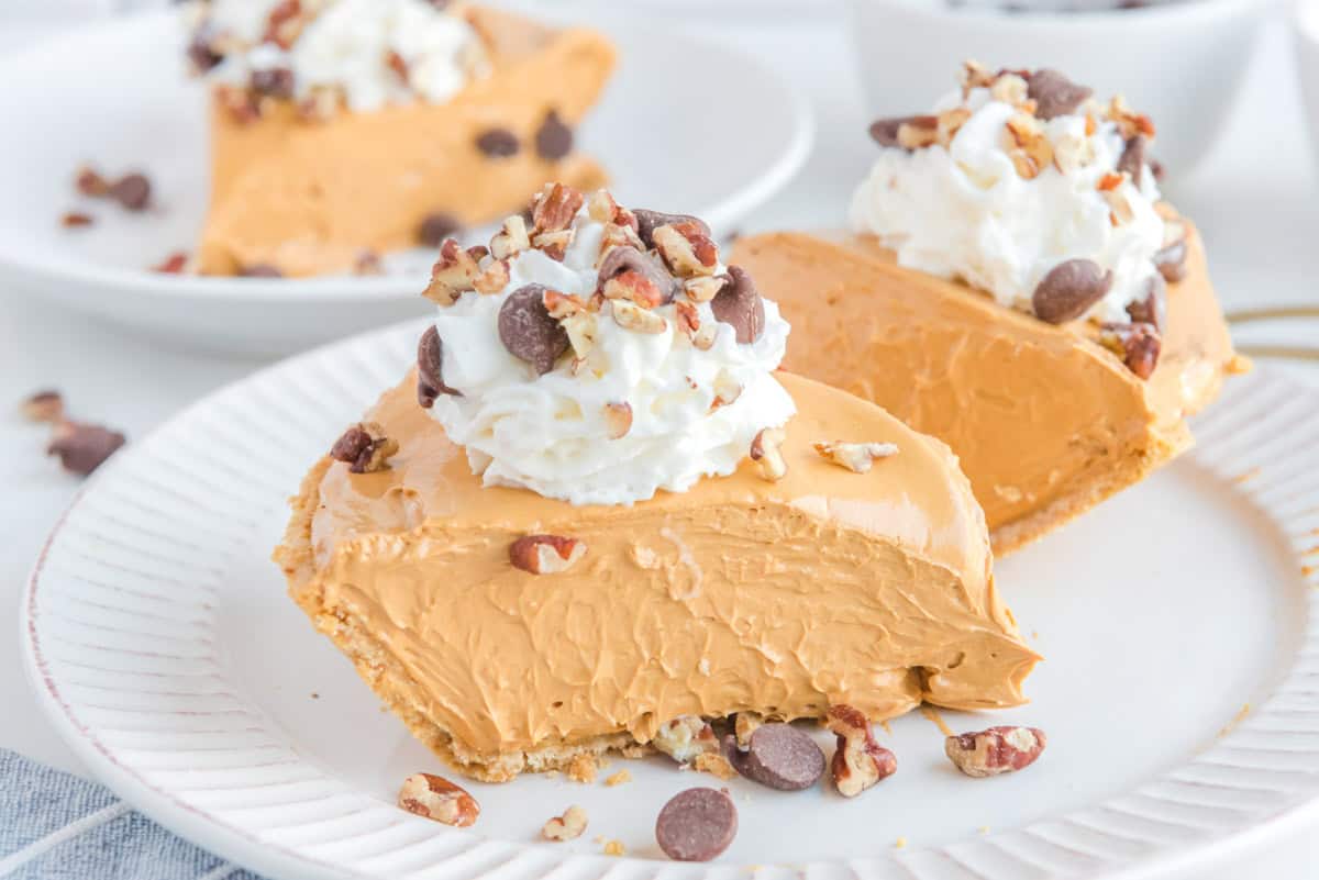 Creamy caramel pie slices topped with whipped cream, chocolate chips, and pecans.
