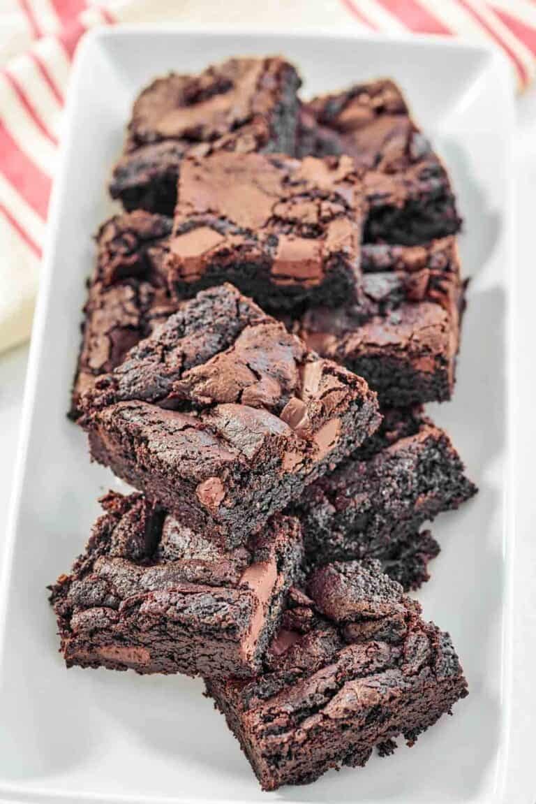 Fudgy chocolate brownies with chocolate chunks on a platter.