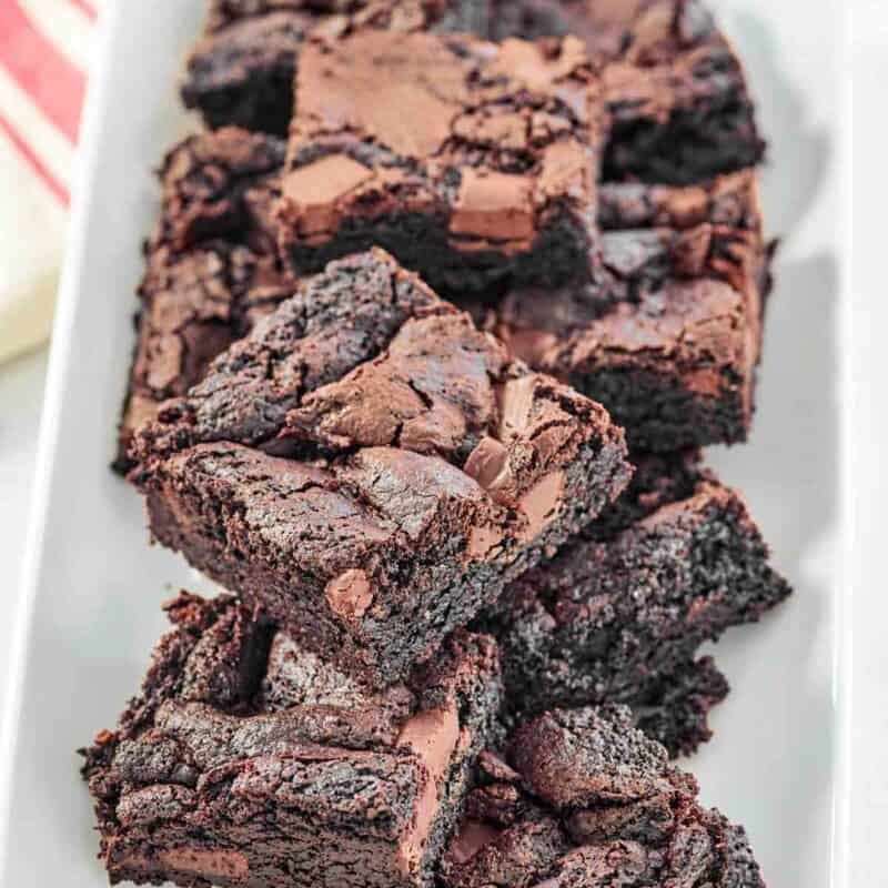 Fudgy chocolate brownies with chocolate chunks on a platter.