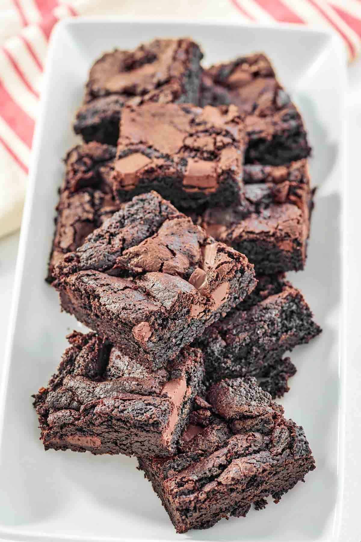 Fudgy chocolate brownies with chocolate chunks on a platter.
