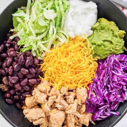 Loaded Mexican chicken rice bowl and a fork on a napkin beside it.