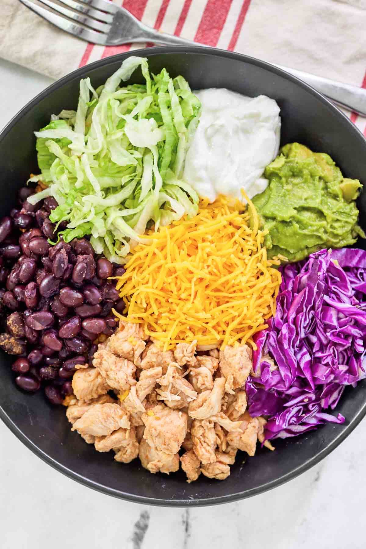 Loaded Mexican chicken rice bowl and a fork on a napkin beside it.