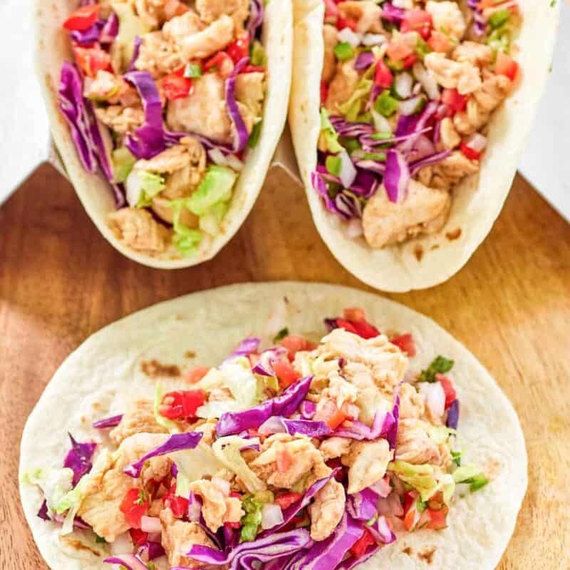Seasoned chicken tacos with fresh toppings in flour tortillas.