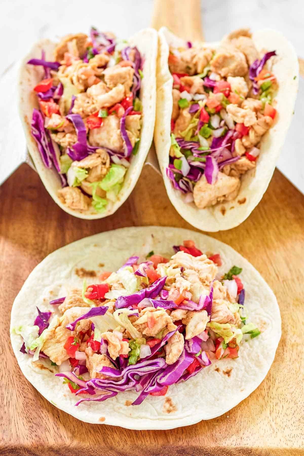 Seasoned chicken tacos with fresh toppings in flour tortillas.