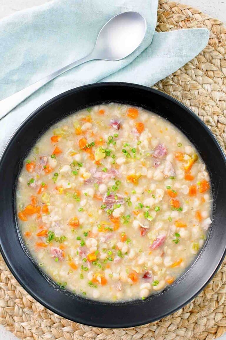 A bowl of soup with vegetables and navy beans.