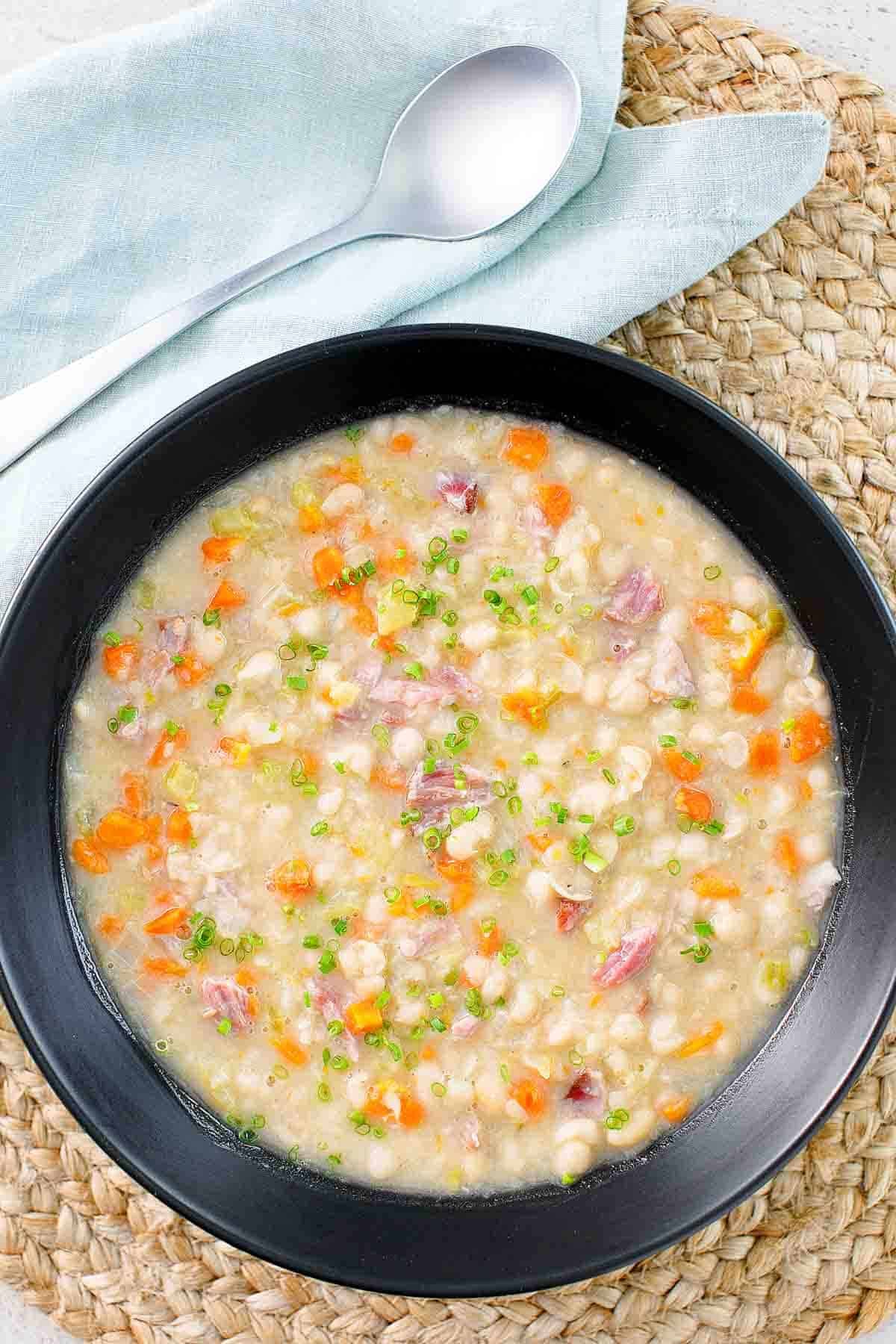 A bowl of soup with vegetables and navy beans.