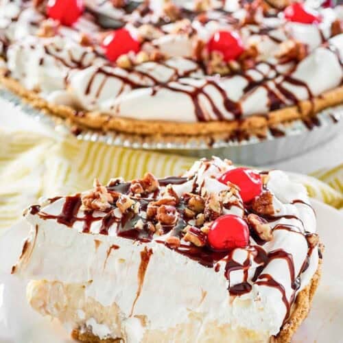 Whipped cream, cherries, pecans, and fudge topped banana pineapple pie.