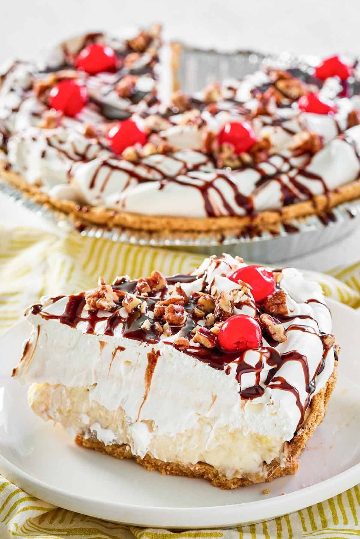 Whipped cream, cherries, pecans, and fudge topped banana pineapple pie.