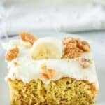 A slice of banana cake with cream cheese frosting on a dessert plate.