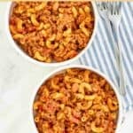 Hearty chili mac and cheese in two bowls and two forks resting on a cloth napkin.