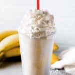 Copycat Fatburger banana milkshake on a coaster and bananas behind it.