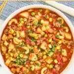 A bowl of hamburger soup made with pasta, potatoes, vegetables, and broth.